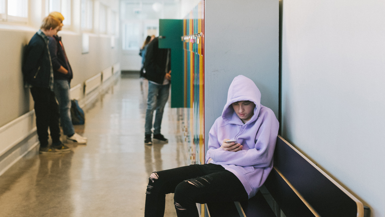 en kille sitter ensam i en skolkorridor