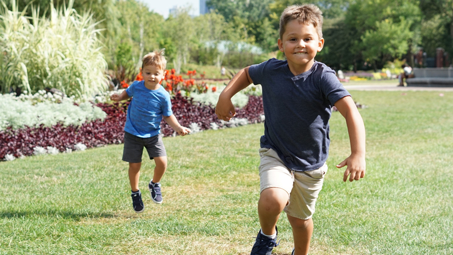 Två barn springer på en gräsmatta.