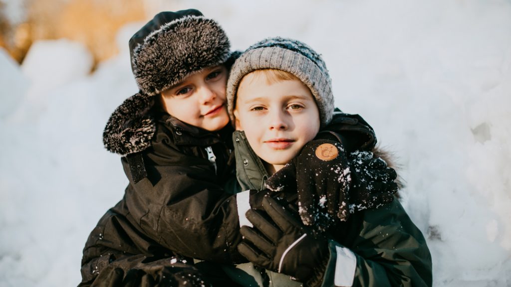 två barn leker i snön på vintern