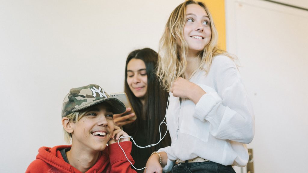 tre tonåringar lyssnar på musik från en mobiltelefon.