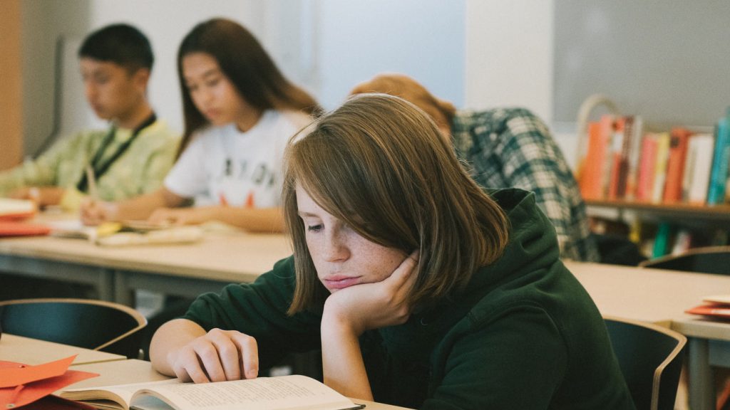 En pojke i klassrummet som läser en bok