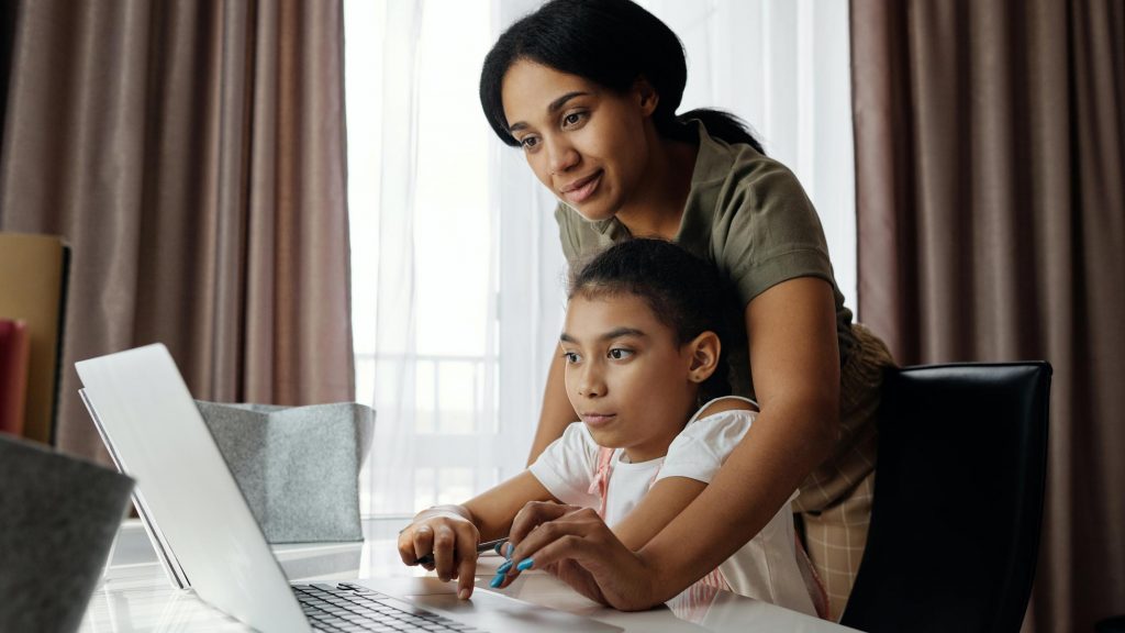 En mamma hjälper en flicka vid en dator