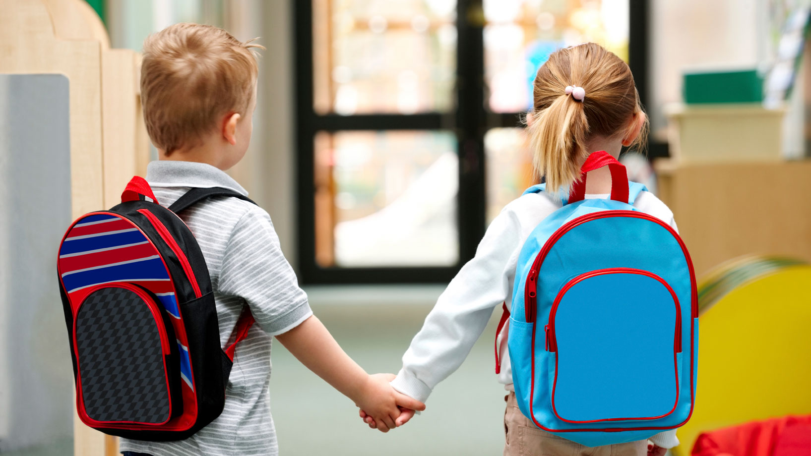 Två barn med skolryggsäckar håller varandra i handen