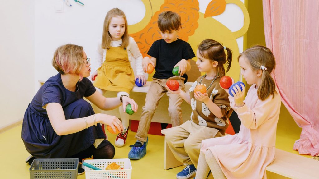 fyra barn och en pedagog pratar i ett klassrum