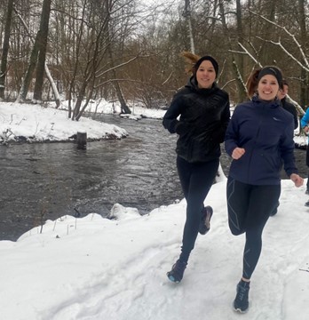 två kvinnor springer i vintermiljö