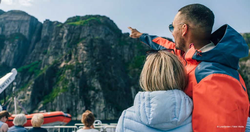 Two people looking up at the Pulpit Rock from Lysefjorden.