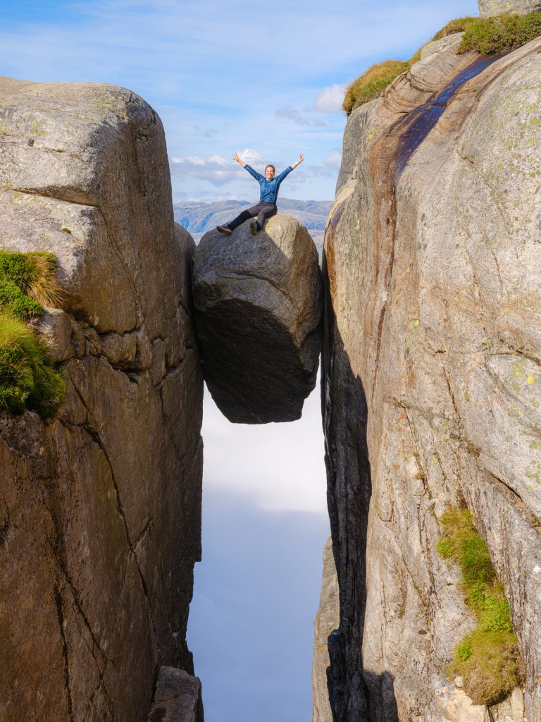 Woman sitting on the Kjeragbolten Sven-Erik Knoff FotoKnoff / Region Stavanger