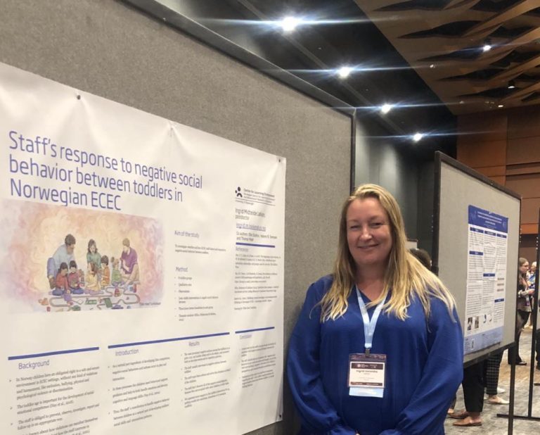 Woman smiling and standing next to a poster.