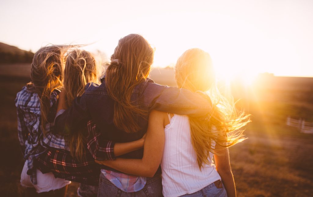 Four girls holding around each other looking at sunset. Photo: GettyImages.
